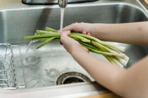 Person washing fresh vegetables in kitchen sink
