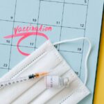 Close-up of a calendar marked for vaccination with a syringe and face mask