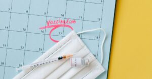 Close-up of a calendar marked for vaccination with a syringe and face mask