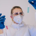 Scientist in full protective gear examining test tubes in a laboratory