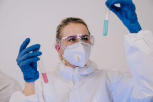 Scientist in full protective gear examining test tubes in a laboratory