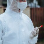 Healthcare worker in protective gear handling a test sample