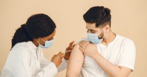 Healthcare worker in protective mask giving a vaccination during the Ebola outbreak response in DRC