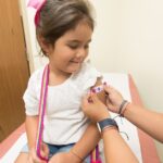 A young child receives a vaccination at a clinic